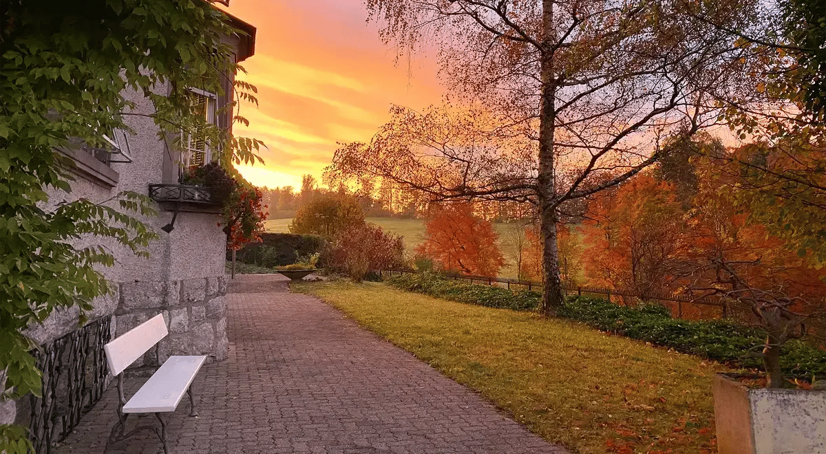 Gartenweg bei Sonnenuntergang mit herbstlicher Landschaft neben dem Gebäude