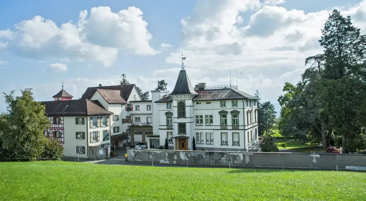Außenansicht des Hauptgebäudes der Tertianum Residenz Schloss Berg hinter einer Steinmauer