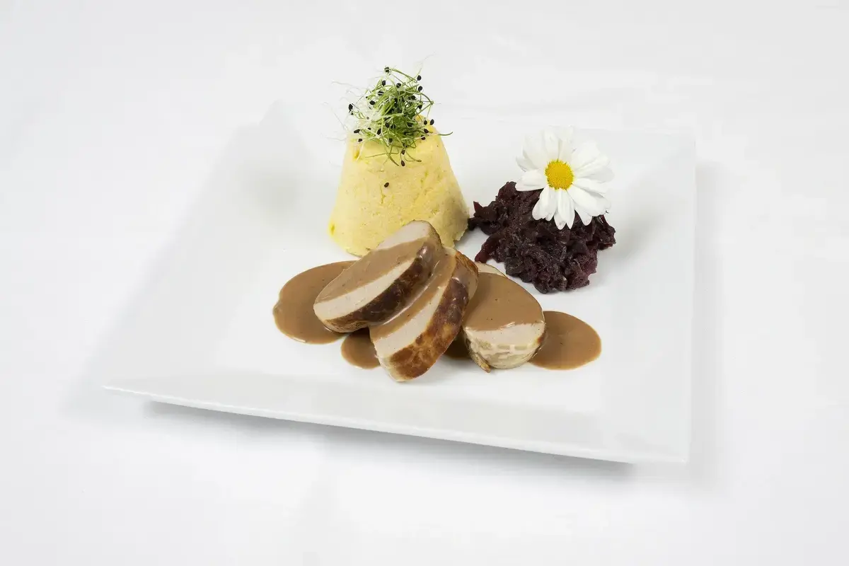 Fleisch mit Sauce, Gemüsepüree und Rotkohl auf einem weißen Teller im Tertianum Bergsicht Restaurant