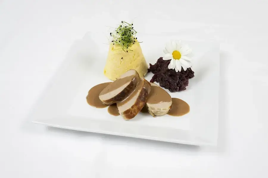 Fleisch mit Sauce, Gemüsepüree und Rotkohl auf einem weißen Teller im Tertianum Bergsicht Restaurant