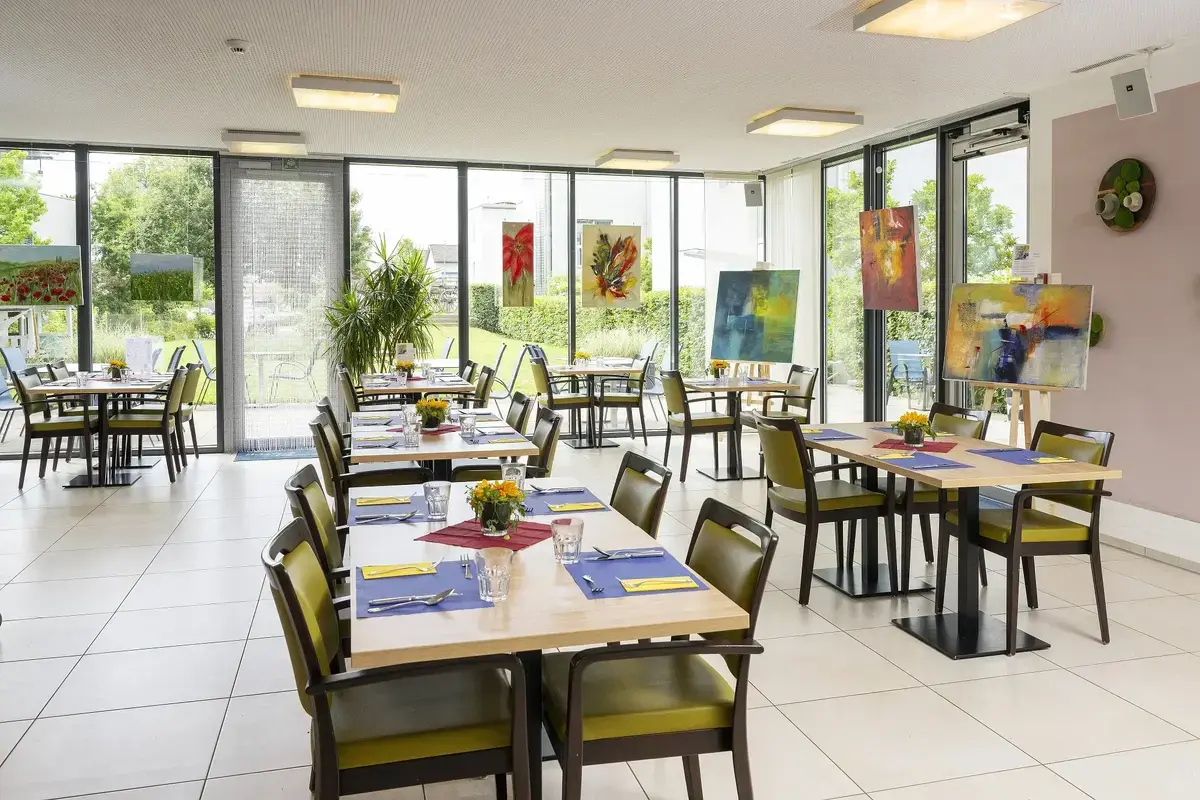 Heller und moderner Innenraum des Tertianum Bergsicht Restaurants mit farbenfrohen Gemälden dekoriert