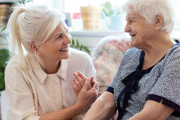 Eine Frau aus dem Tertianum lacht und unterhält sich mit einer älteren Dame, die ihr gegenüber sitzt